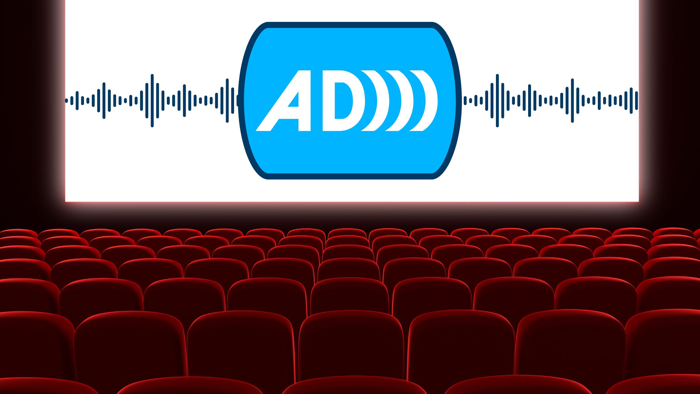 Cinema auditorium, rows of chairs, audio descriptor symbol on screen: capital letters AD.