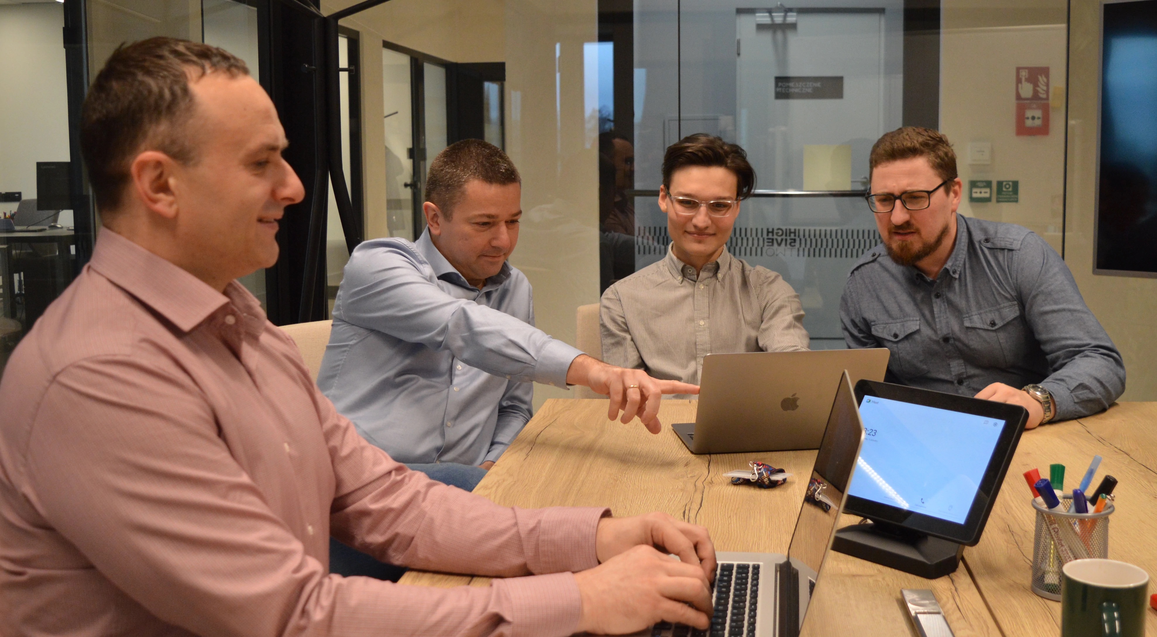 Zdjęcie czterech współzałożycieli Accens siedzących przed laptopami w sali konferencyjnej.